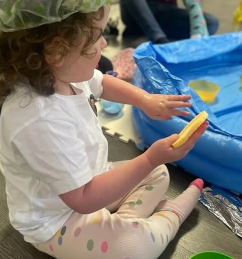 Picture of a child paying with water and a sponge at a Sense-a-Story session