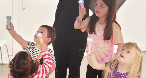 four children using torches to light up a ceiling and looking up