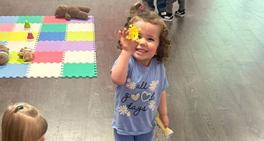 a child holding a plastic frog to the camera and smiling