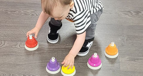 a child bending over and playing with bells to make sounds in a sensory workshop