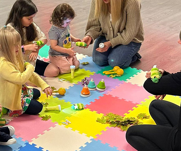 an adult passing caterpillar toys to children to touch and play with in a sensory storytelling session