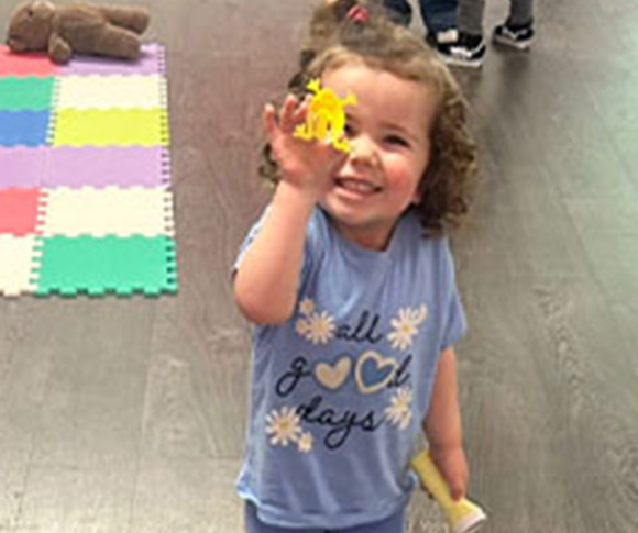 a child holding a plastic frog up to the camera