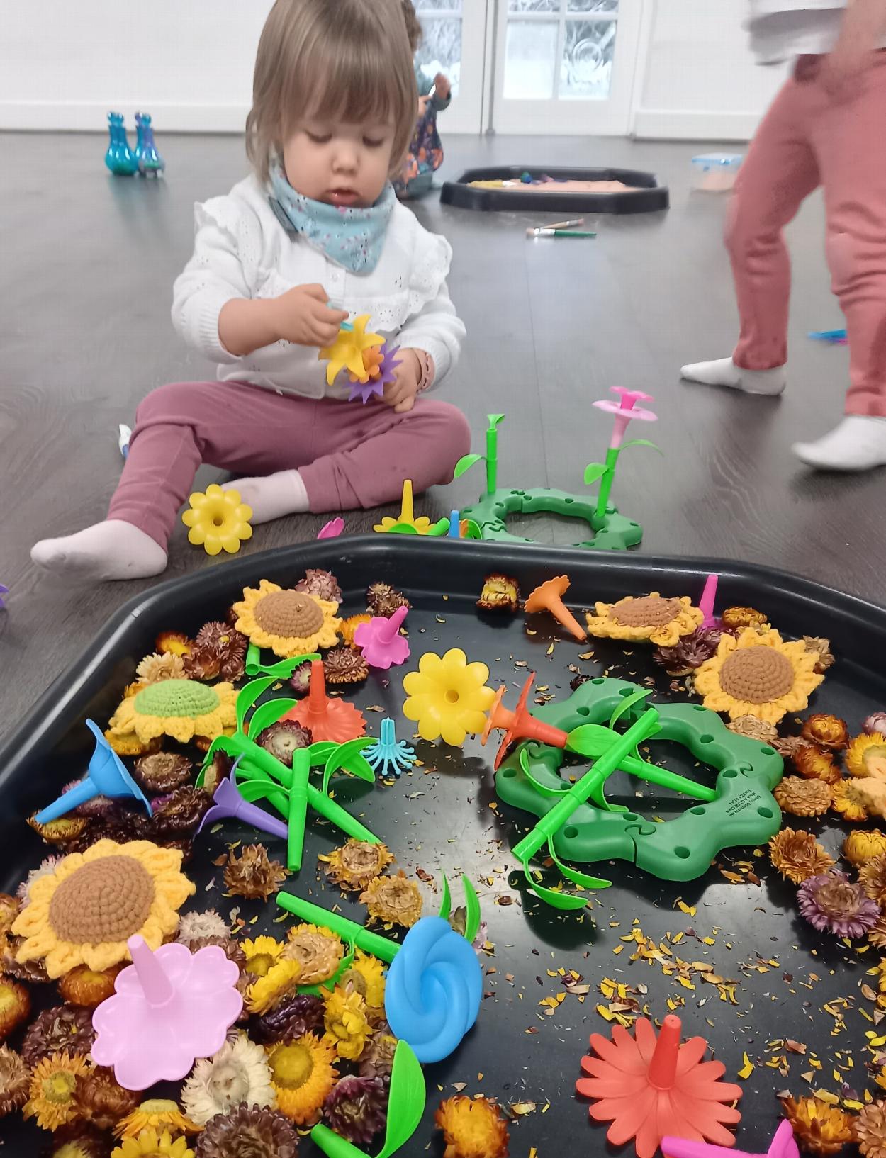 A child playing with real and artificial flowers at a sensory birthday party